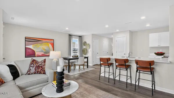 a living room with furniture kitchen view and a wooden floor