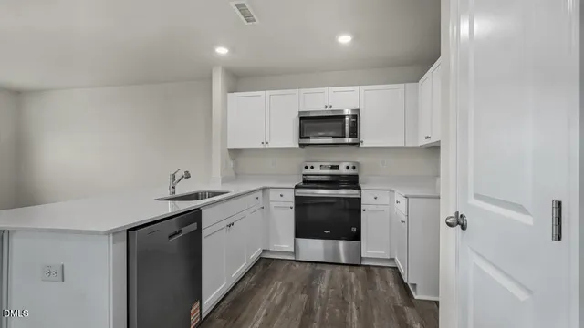a kitchen with a sink a stove top oven and wooden floor