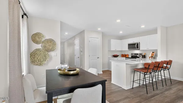 a kitchen with stainless steel appliances granite countertop a dining table chairs and stove