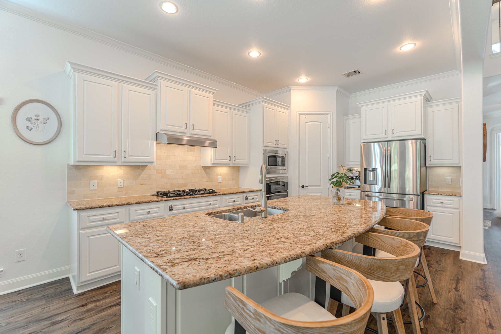 30 Fury Ranch Place The Woodlands, TX 77375 - Photo 16 of 47 This modern kitchen features elegant granite countertops, a spacious island with seating, stainless steel appliances, and ample white cabinetry, creating a bright and inviting space perfect for cooking and entertaining.
