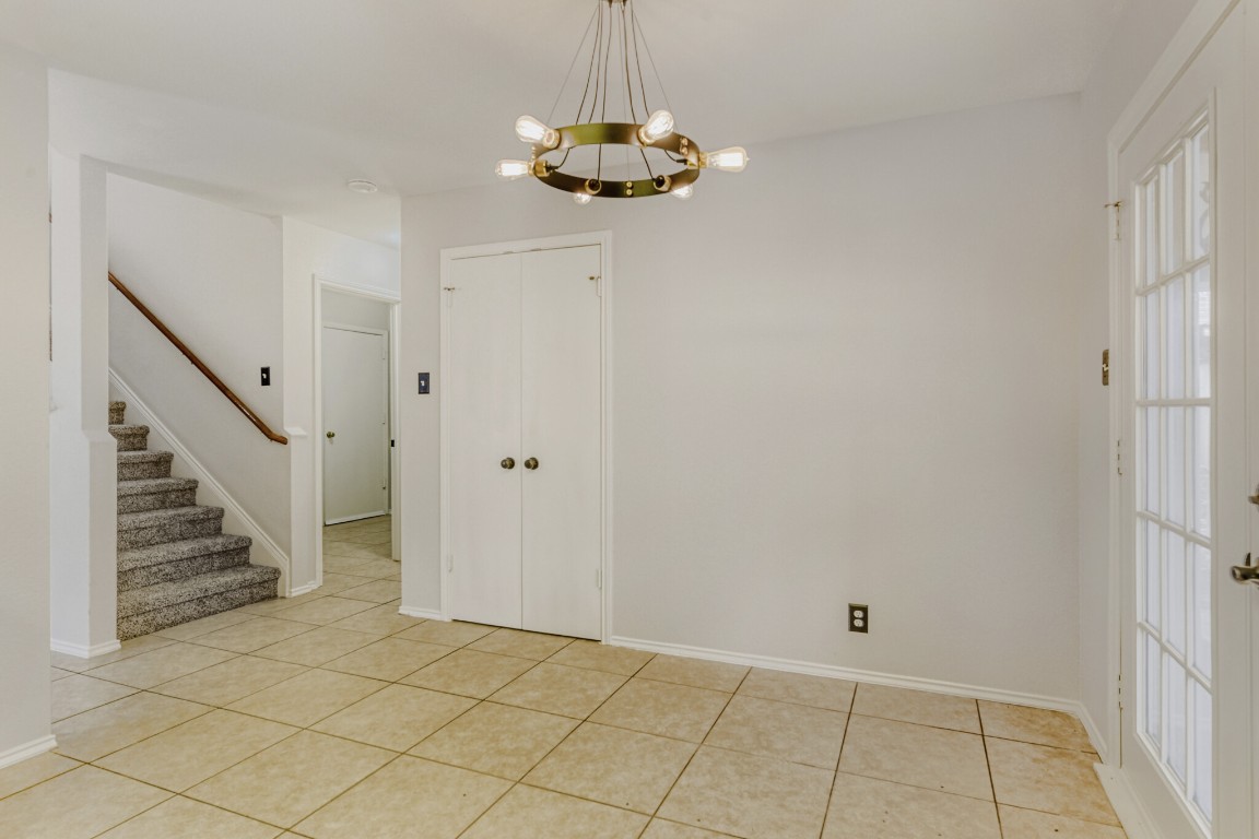 4010 Reeders Drive Austin, TX 78725 - Photo 12 of 26 Empty room with stairs, a chandelier, and light tile patterned floors