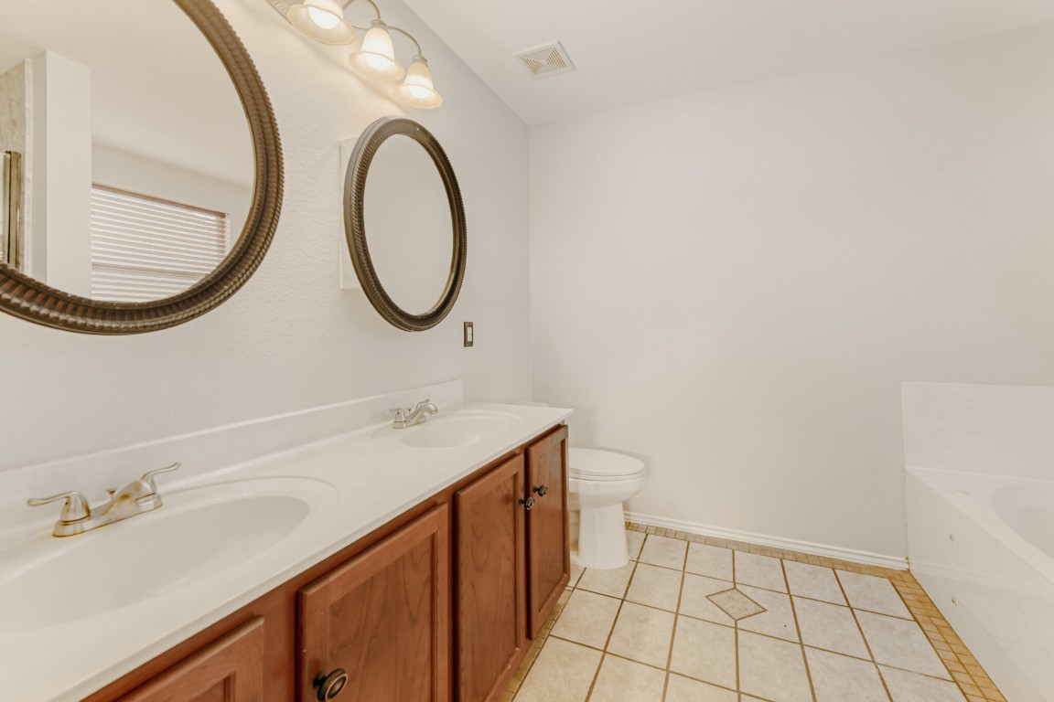 4010 Reeders Drive Austin, TX 78725 - Photo 23 of 26 Bathroom with double vanity, a bath, and light tile patterned flooring