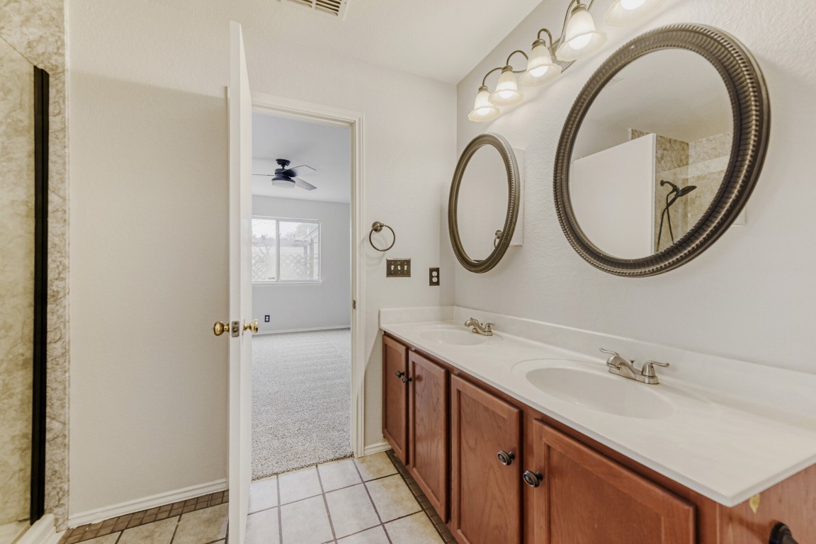 4010 Reeders Drive Austin, TX 78725 - Photo 25 of 26 Full bathroom featuring double vanity, a shower, light tile patterned floors, light carpet, and ceiling fan