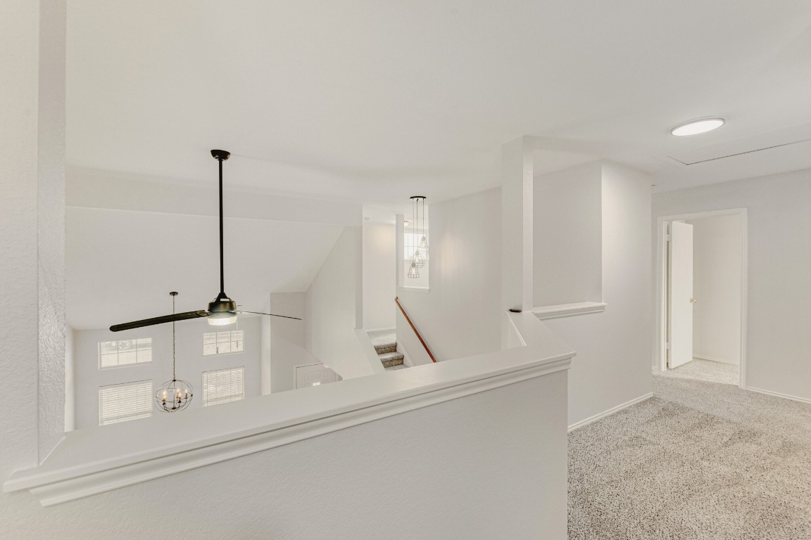 4010 Reeders Drive Austin, TX 78725 - Photo 6 of 26 Hallway with light colored carpet, an upstairs landing, and a chandelier