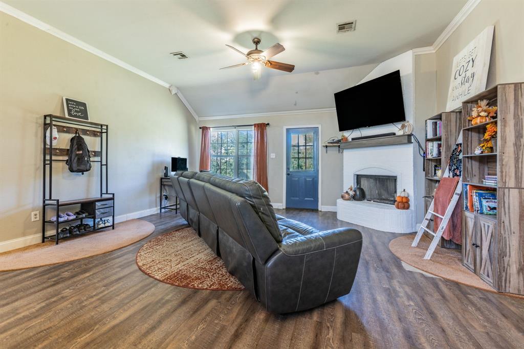 4930 Spring Valley Road Lorena, TX 76655 - Photo 3 of 34 Vaulted ceiling with a ceiling fan, wood-finish flooring, white painted fireplace with a mantel, and a blue painted door with window panes