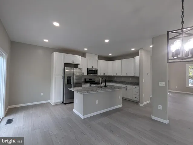 a kitchen with stainless steel appliances kitchen island granite countertop a refrigerator and a stove top oven