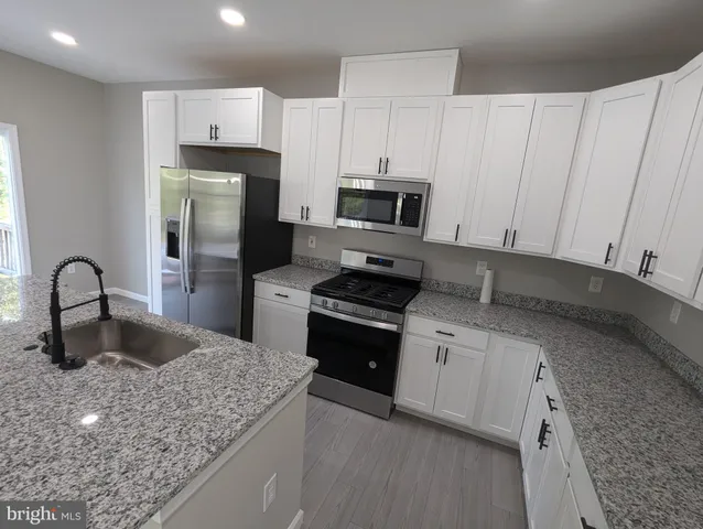 a kitchen with kitchen island granite countertop a sink stainless steel appliances and cabinets