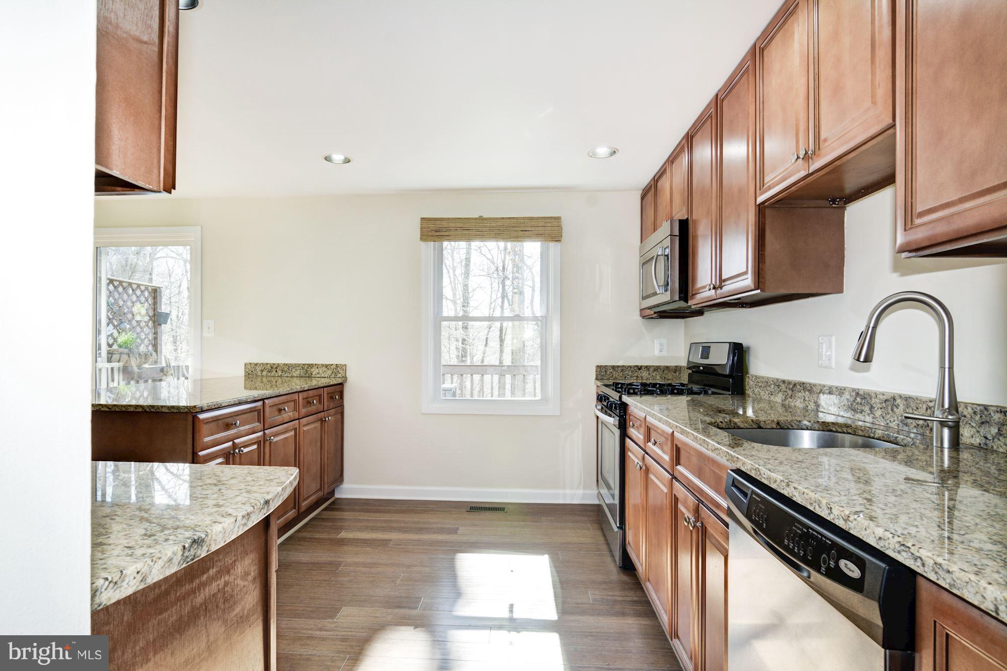 7621 Fallswood Way Lorton, VA 22079 - Photo 12 of 26 a kitchen with granite countertop a sink a stove and cabinets