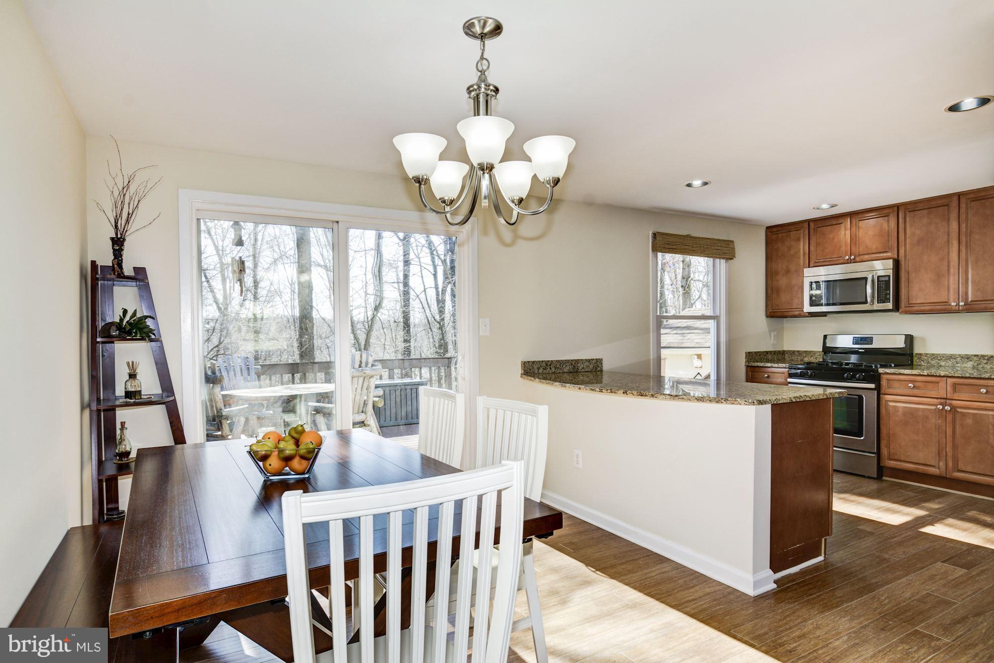 7621 Fallswood Way Lorton, VA 22079 - Photo 8 of 26 a kitchen with stainless steel appliances granite countertop a stove a refrigerator a sink dishwasher a dining table and chairs with wooden floor