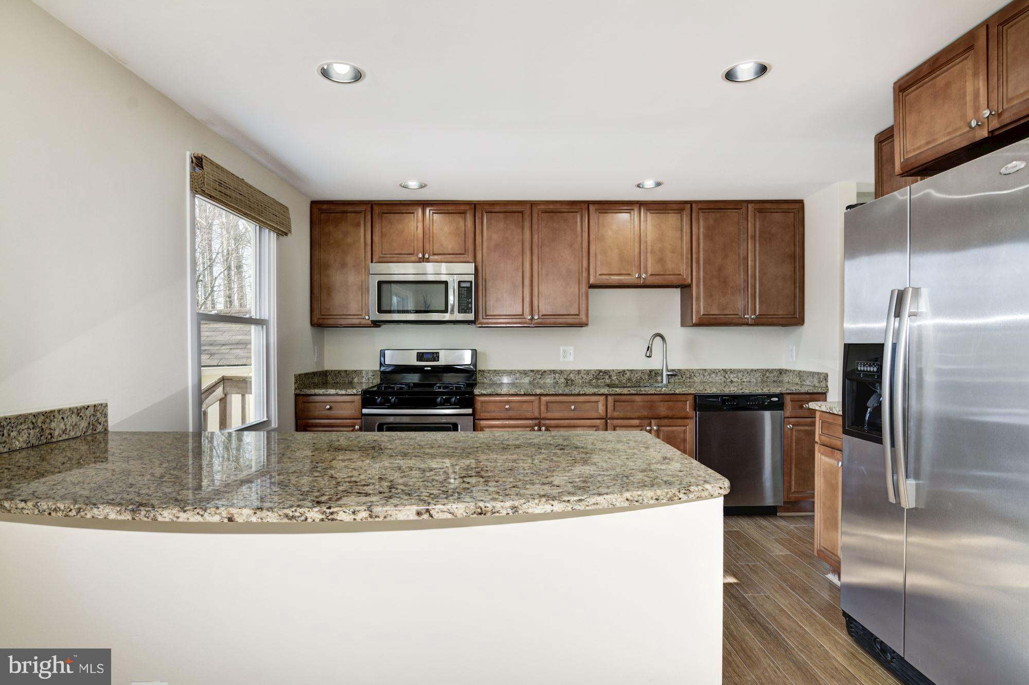 7621 Fallswood Way Lorton, VA 22079 - Photo 9 of 26 a kitchen with kitchen island granite countertop a sink stove and refrigerator