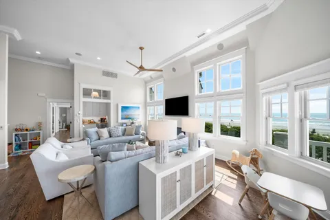 a living room with furniture a flat screen tv and large windows