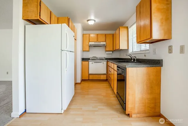 a kitchen with stainless steel appliances granite countertop a refrigerator a stove a sink and a microwave