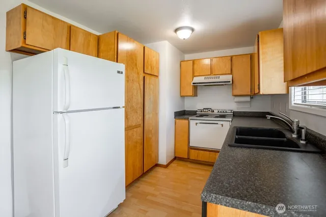 a kitchen with a refrigerator a stove top oven a sink and cabinets