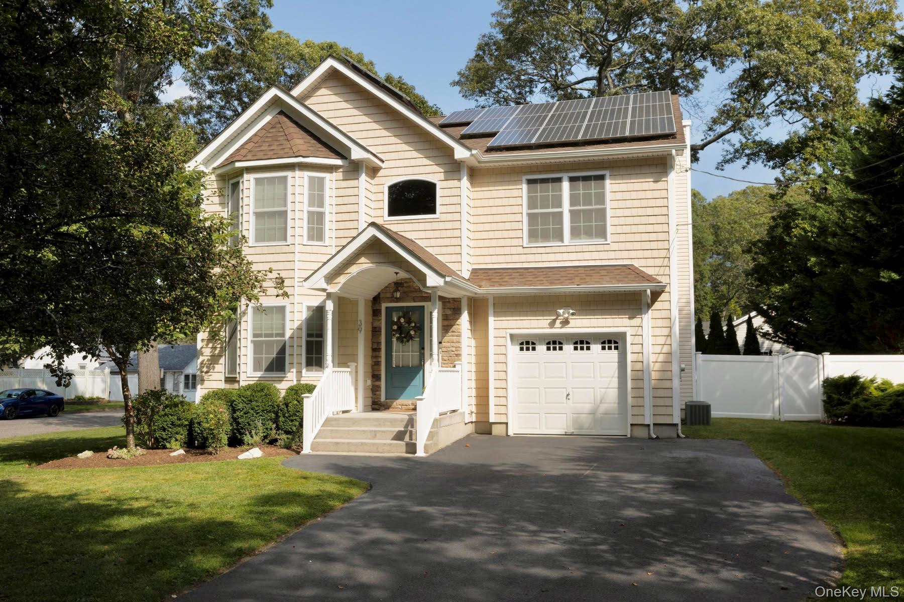 View of front of house with an attached garage, a gate, solar panels, and driveway