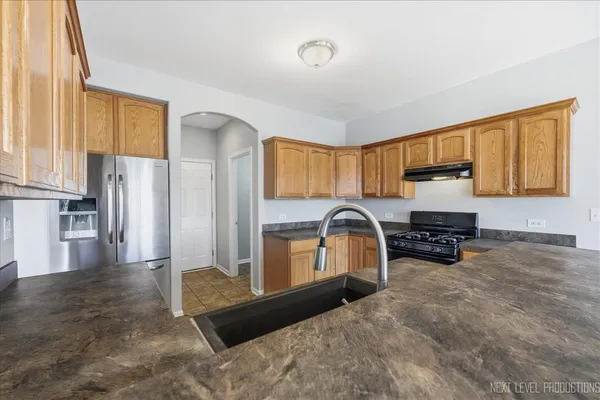 a kitchen with stainless steel appliances granite countertop a refrigerator a stove a sink and a cabinets with wooden floor