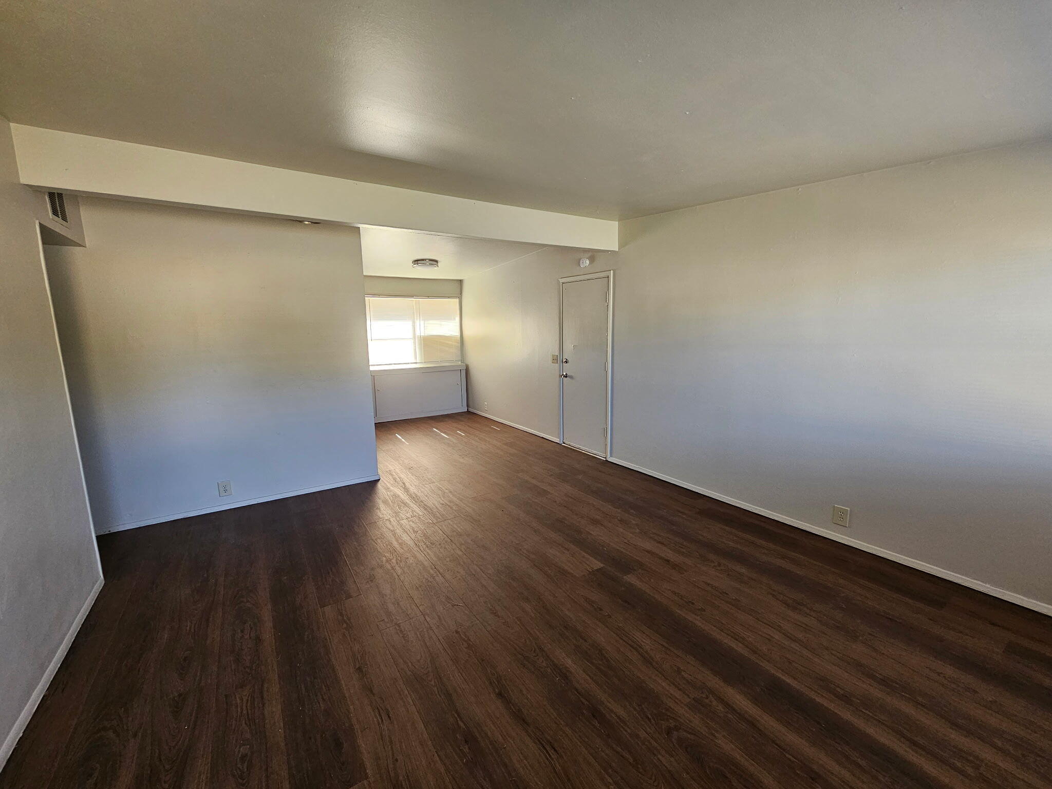 2703 66th Street Lubbock, TX 79413 - Photo 2 of 8 a view of an empty room with wooden floor and a window