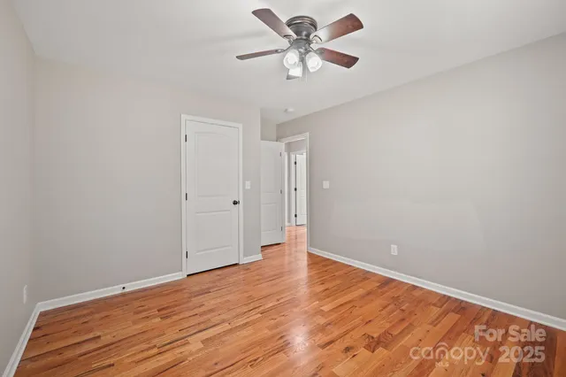 a view of a big room with wooden floor and a chandelier fan