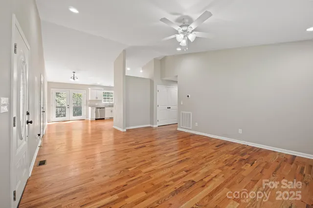 a view of an empty room with window and wooden floor