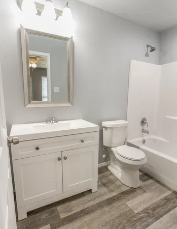 a bathroom with a granite countertop toilet a sink and a mirror