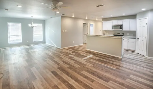 a view of kitchen with kitchen island wooden floors appliances and cabinets