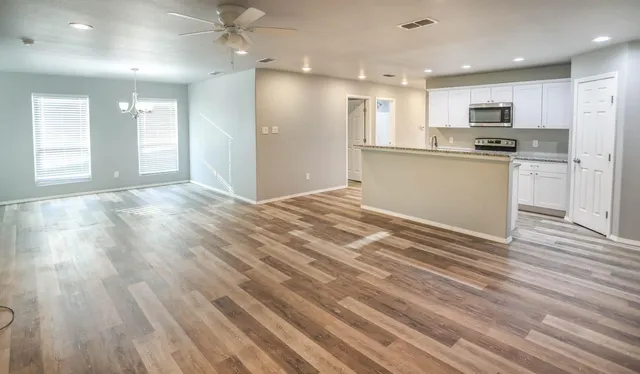 a view of kitchen with kitchen island wooden floors appliances and cabinets