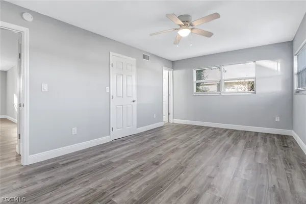 an empty room with wooden floor and windows