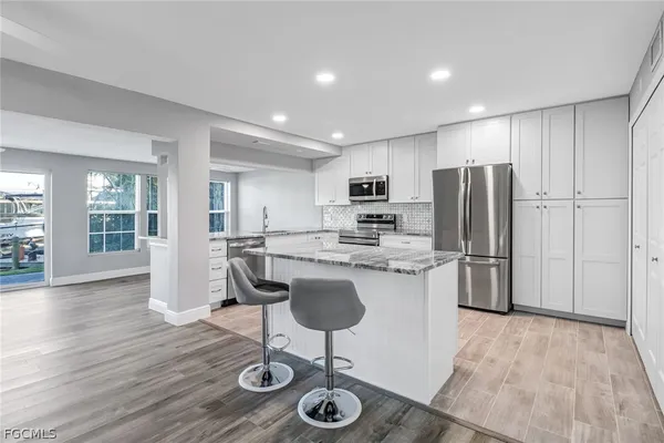 a kitchen with stainless steel appliances granite countertop a refrigerator a stove top oven a sink dishwasher and a refrigerator with wooden floor