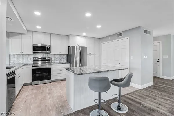 a kitchen with stainless steel appliances granite countertop a stove a sink a refrigerator and a microwave