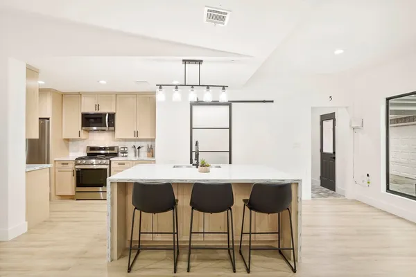 a kitchen with stainless steel appliances kitchen island a table and chairs in it