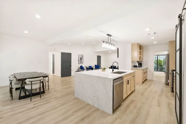 a large white kitchen with wooden floor and a sink