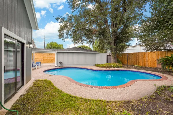 a view of pool with table and chairs under an umbrella