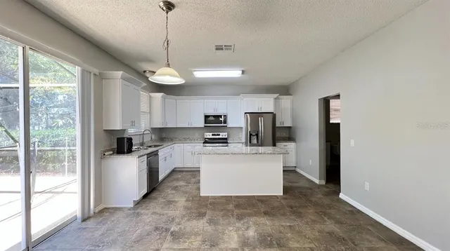 a kitchen with granite countertop a center island a stove a refrigerator cabinets a dining table and chairs