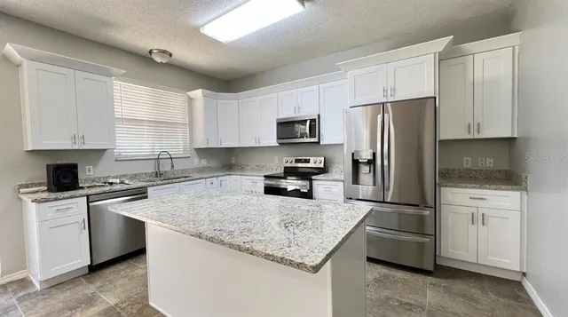 a kitchen with a refrigerator a sink a stove a microwave and cabinets