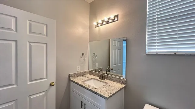 a bathroom with a granite countertop sink and a mirror