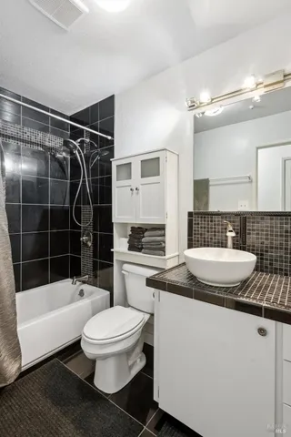 a bathroom with a granite countertop sink a toilet a mirror and bathtub