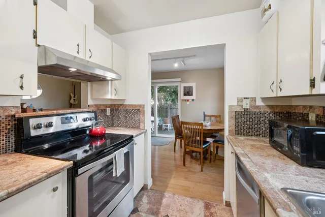 a kitchen with a stove cabinets and chairs