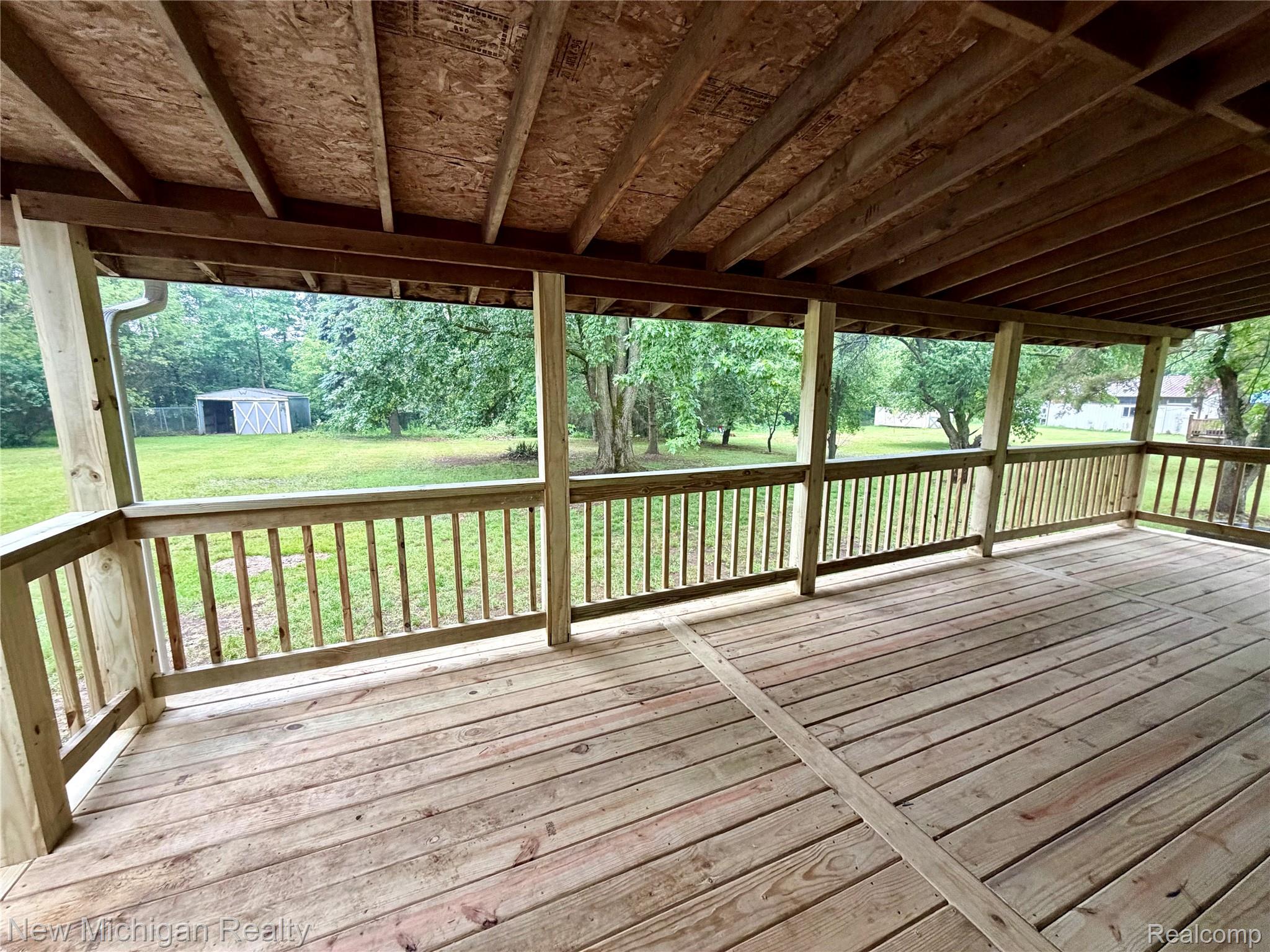 7104 Willard Road Millington, MI 48746 - Photo 7 of 30 Expansive covered wood deck with full railing overlooking a verdant backyard
