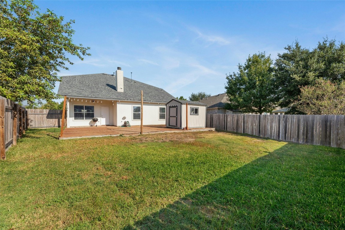 18401 Masi Loop Pflugerville, TX 78660 - Photo 27 of 29 Rear view of property featuring a chimney, a shed, a fenced backyard, and roof with shingles