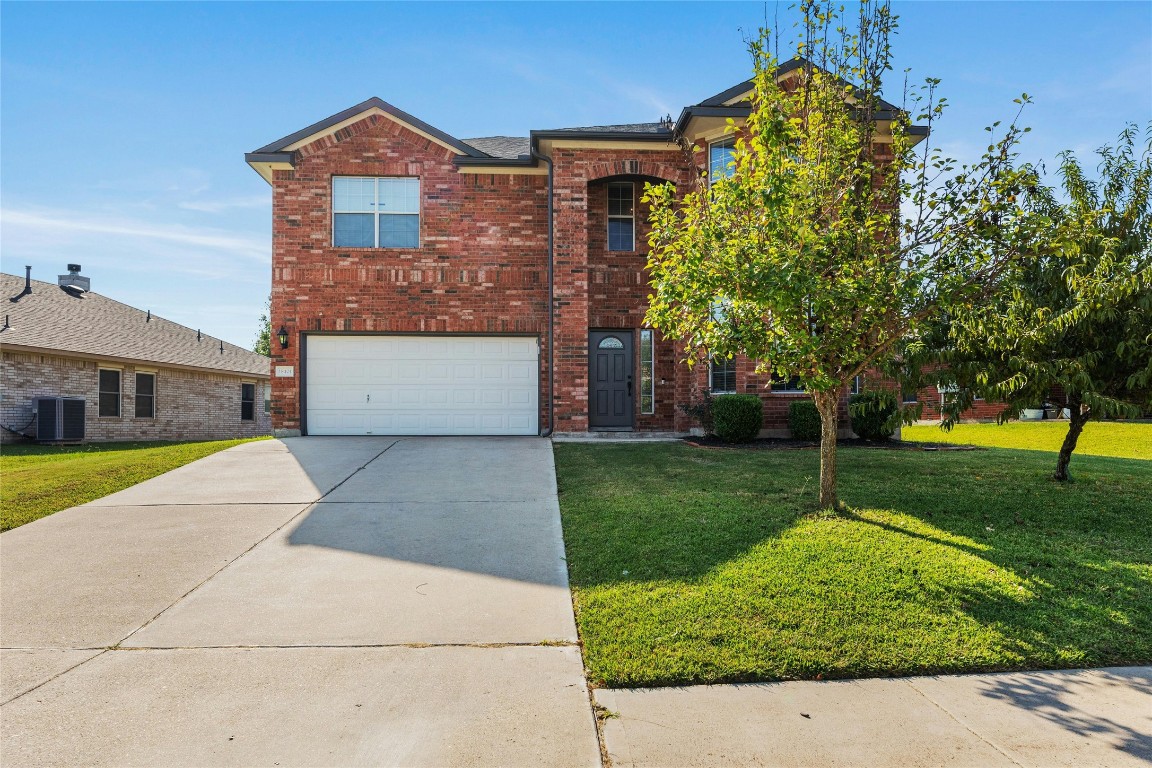 18401 Masi Loop Pflugerville, TX 78660 - Photo 5 of 29 Traditional home featuring concrete driveway, brick siding, a front yard, and a garage