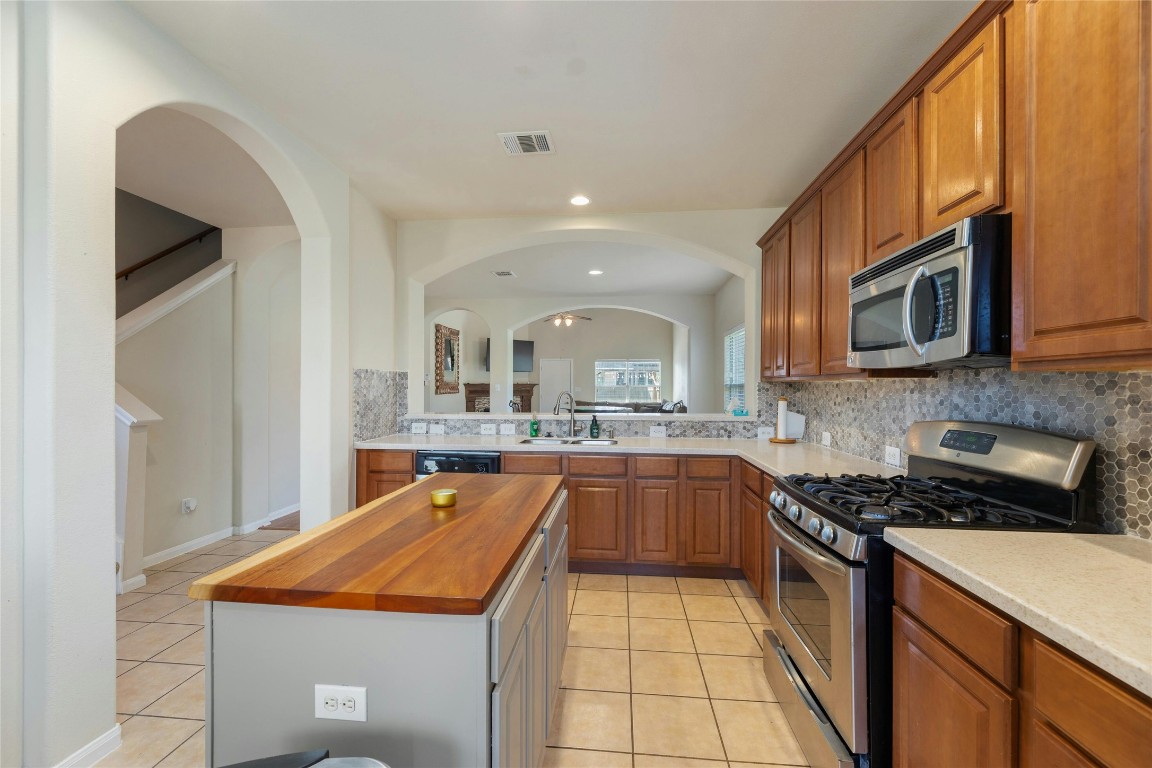 18401 Masi Loop Pflugerville, TX 78660 - Photo 8 of 29 Kitchen with stainless steel appliances, light tile patterned floors, tasteful backsplash, a kitchen island, and brown cabinets