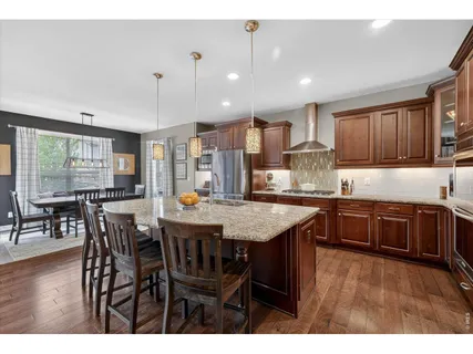 a kitchen view with granite countertop a stove a dining table and chairs with wooden floor