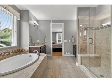 a bathroom with a granite countertop sink a mirror a bathtub and shower