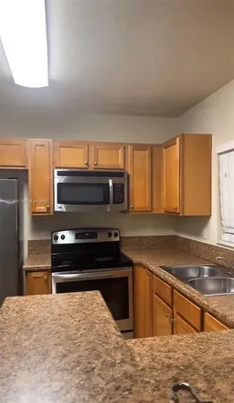 a kitchen with stainless steel appliances kitchen island granite countertop a stove a sink and a microwave