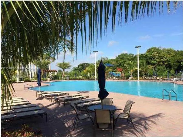 a view of a backyard with lawn chairs under an umbrella with wooden fence