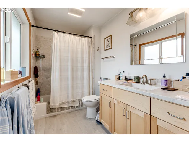 a bathroom with a granite countertop sink a mirror a toilet and a shower
