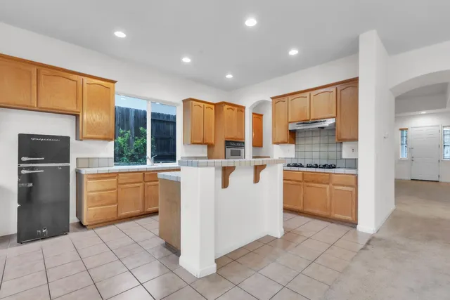 a kitchen with kitchen island granite countertop wooden cabinets and white appliances