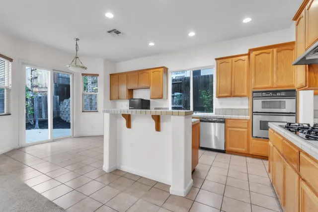 a kitchen with kitchen island granite countertop a stove top oven a sink a counter top space and cabinets