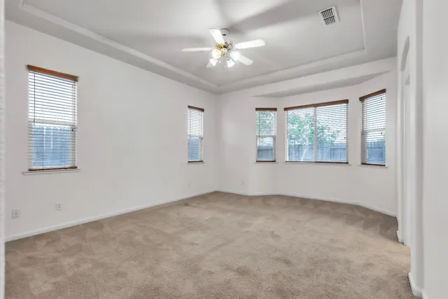 an empty room with windows and chandelier fan