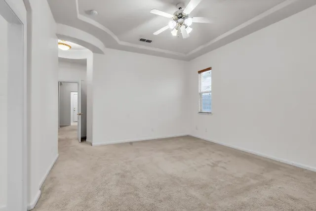 an empty room with chandelier fan and windows