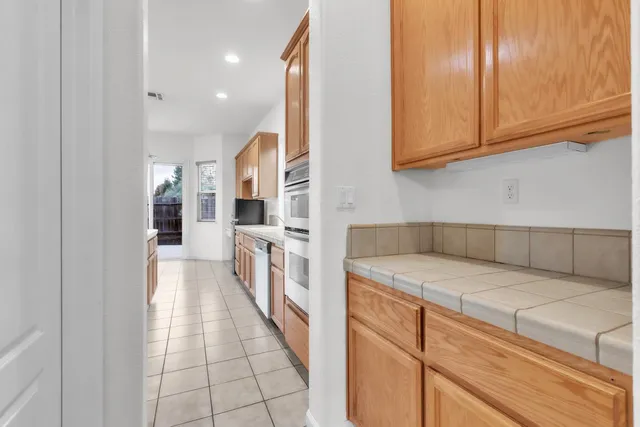a hallway view with stainless steel appliances granite countertop furniture and a view of living room